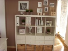 a white bookcase with baskets and pictures on it