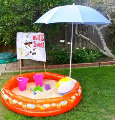 an inflatable pool with sand and toys on the lawn next to a sign that says ollie's summer