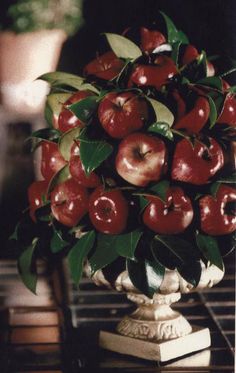 a vase filled with lots of apples on top of a table