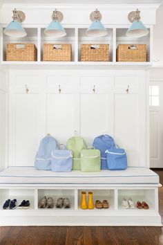 a white bench with baskets on top of it and two lamps hanging above the bench