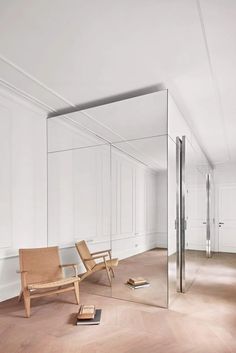 a chair sitting in front of a large mirror on the floor next to a book