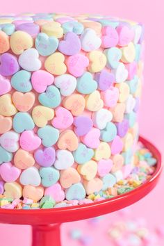 a heart shaped cake on top of a red plate with sprinkles around it