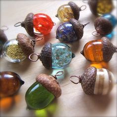 there are many different colored glass beads on the table with acorns in them