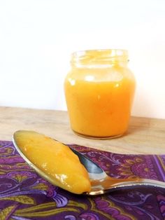 a spoon sitting on top of a wooden table next to a jar of orange juice