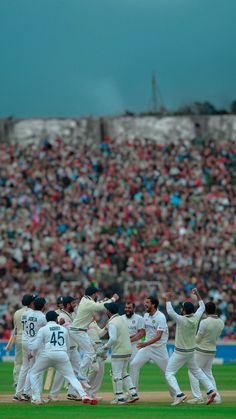 a group of men standing on top of a field next to each other in front of a crowd