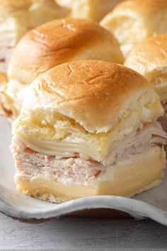 two ham and cheese sliders sitting on a plate with rolls in the back ground