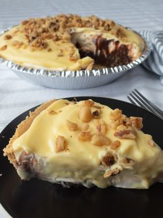 two pies sitting on top of black plates with silverware next to each other