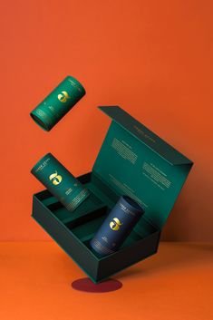 an open box with two empty bottles in it on top of a table next to orange wall