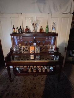 an old piano with many bottles and glasses on it