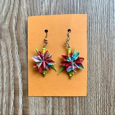 a pair of earrings with colorful paper flowers on them