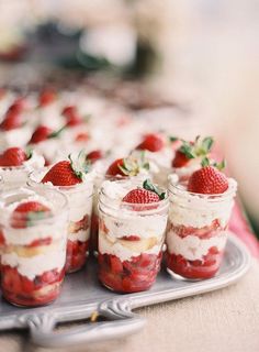 strawberry shortcakes with whipped cream and fresh strawberries in jars on a tray