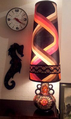 a lamp sitting on top of a wooden table next to a wall mounted clock and seahorse