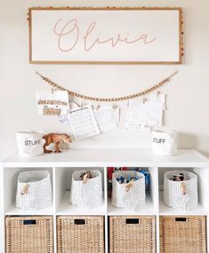 a white dresser topped with baskets next to a sign that says elivia on it