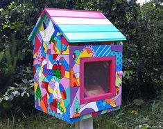 a brightly colored bird house in the grass