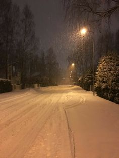 a snow covered street at night with the lights on