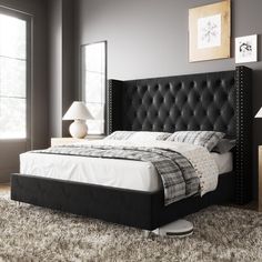 a bed with a black headboard and foot board in a room next to two windows