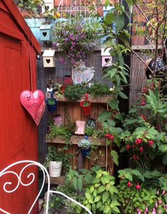 an outdoor garden with lots of potted plants and flowers in the corner, including heart shaped planters