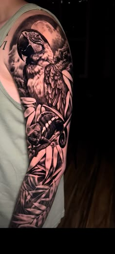 a man's arm with a bird and leaves tattoo on it