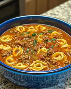 a blue bowl filled with pasta and meat soup