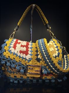 a crocheted purse on display in a dark room with the handle extended to it's side