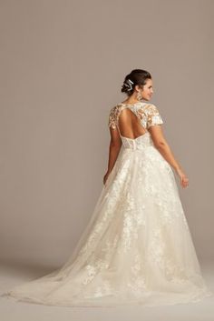 a woman in a wedding dress with an open back and floral appliques on the shoulders