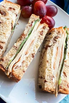 turkey and raisin bread finger sandwiches on a white plate with grapes next to it