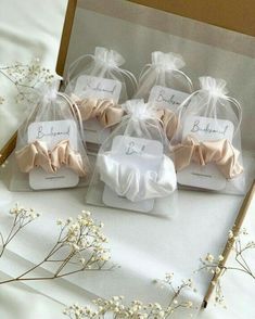 four small wedding favors in organ bags on a white tablecloth with baby's breath flowers