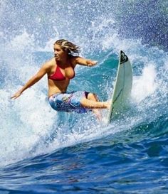 a woman riding a wave on top of a white surfboard in the blue ocean