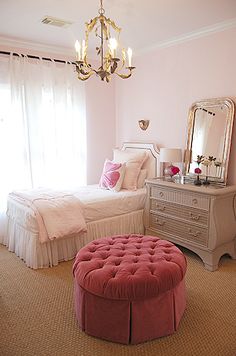 a bedroom with two beds and a pink ottoman