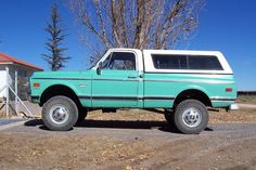 an old green truck parked in front of a house