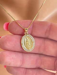 "This is a beautiful gold filled our lady of Guadalupe pendant necklace. This necklace features a 18K gold filled Guadalupe pendant, measures 22X15mm and hangs on a 6mm bale. Chain is a 14K gold filled box chain with spring clasp in back. This is a beautiful Guadalupe image surrounded by pave crystals that make it sparkle on this gorgeous shiny box chain that catches light with movement.  Necklace is completely gold filled. Comes in a gift box ready to present. Please check out my shop, as I sell many beautiful Guadalupe pendant necklaces. You can go to my shop front page and search for \"Guadalupe\" in the search bar. Message me if you have any questions. All my jewelry is handmade and made to order.  Please pay attention to delivery time on this listing. I do offer shipping upgrades at c Oval Our Lady Of Guadalupe Necklace For Gift, Oval Our Lady Of Guadalupe Necklace Gift, Our Lady Of Guadalupe Round Pendant As Gift, Gold Plated Miraculous Medal Jewelry As Gift, Gold Virgin Mary Necklace Gift, Gold Our Lady Of Guadalupe Necklace Gift, Oval Virgin Mary Jewelry Gift, Lady Of Guadalupe Necklace, Guadalupe Necklace