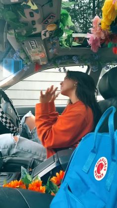 a woman sitting in the back seat of a car with flowers on her head and hands up