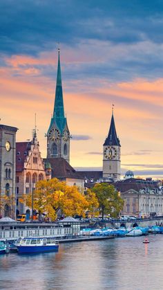 boats are parked on the water in front of buildings and a clock tower at sunset