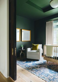 a living room with green walls and white furniture