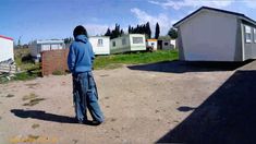 a man is standing in front of some small houses and trailer parkes on the other side of the road