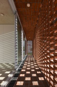 an empty hallway with brick walls and shadows on the floor