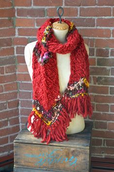 a red scarf sitting on top of a mannequin's dummy next to a brick wall