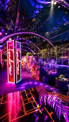 an indoor event venue with purple lighting and floral arrangements on the walls, decorated in neon colors