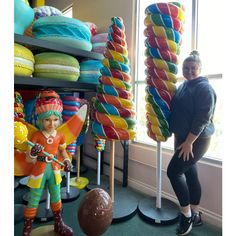 a woman is standing next to some colorful candy canes and a ball in front of her