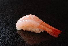 a piece of sushi sitting on top of a black counter