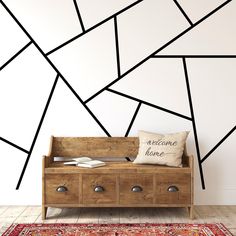 a wooden bench sitting in front of a wall with black and white lines on it