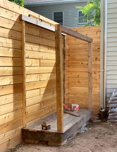 a wooden bench sitting in the middle of a yard next to a fence and building