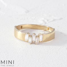 a gold ring with three baguettes on it, sitting on a white surface