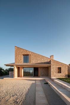 the house is made out of stone and has an open front door that leads to another room