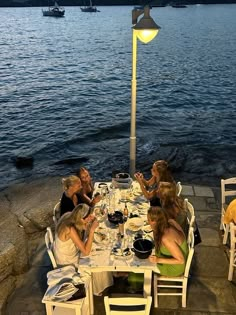 four women sitting at a table outside by the water