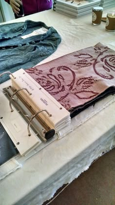 an open book sitting on top of a table next to some folded up jeans and other items