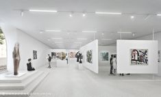 people are looking at art on display in an open space with white walls and flooring