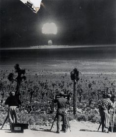 several people are standing in the desert with their skis and poles, looking at the sun