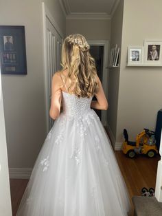 a woman in a white wedding dress looking at herself in the mirror with her back to the camera