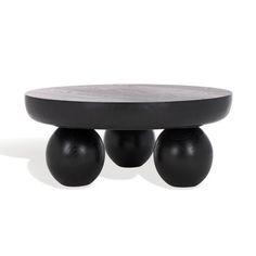 three black balls sitting on top of a wooden table next to an oval shaped object